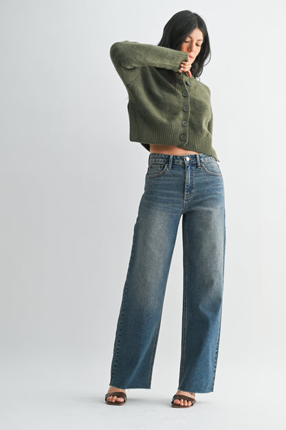 Woman wearing a green cropped sweater and blue jeans on a white background
