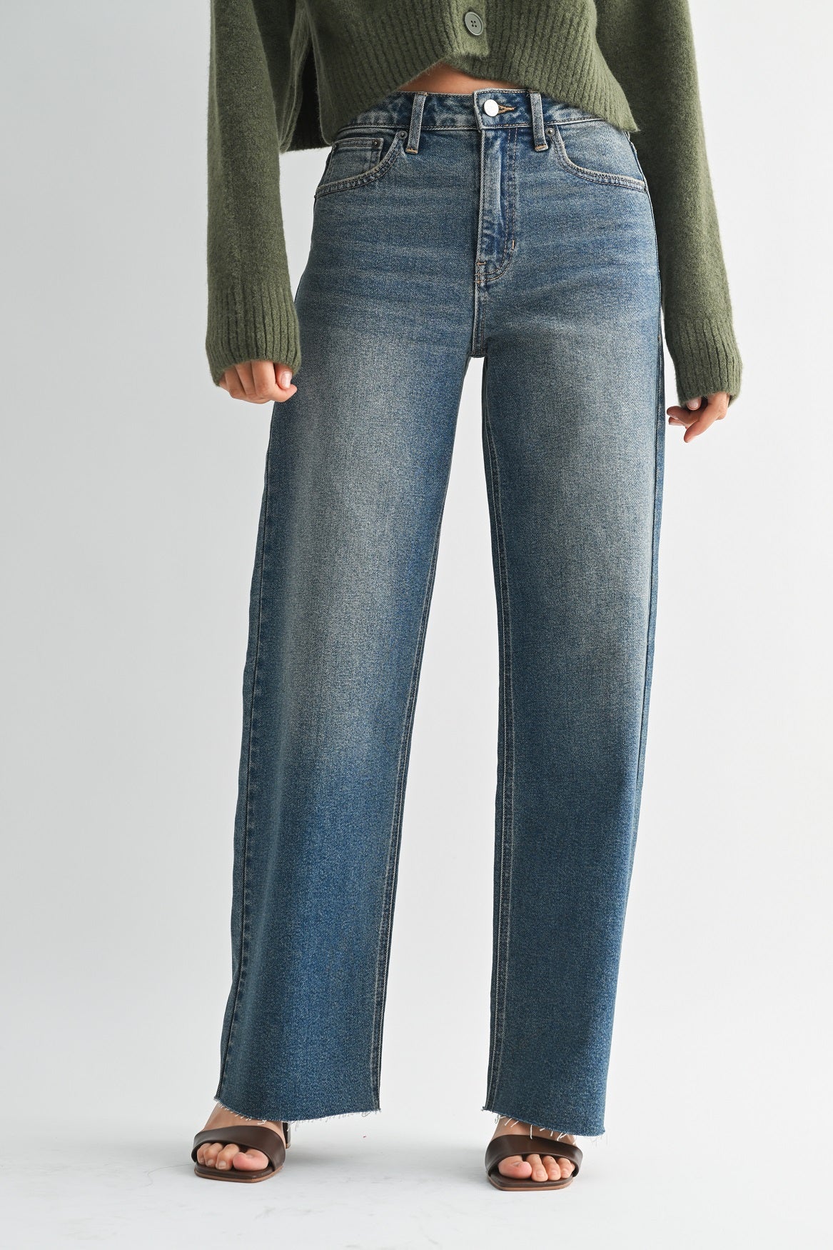 Person wearing blue jeans and a green sweater on a white background