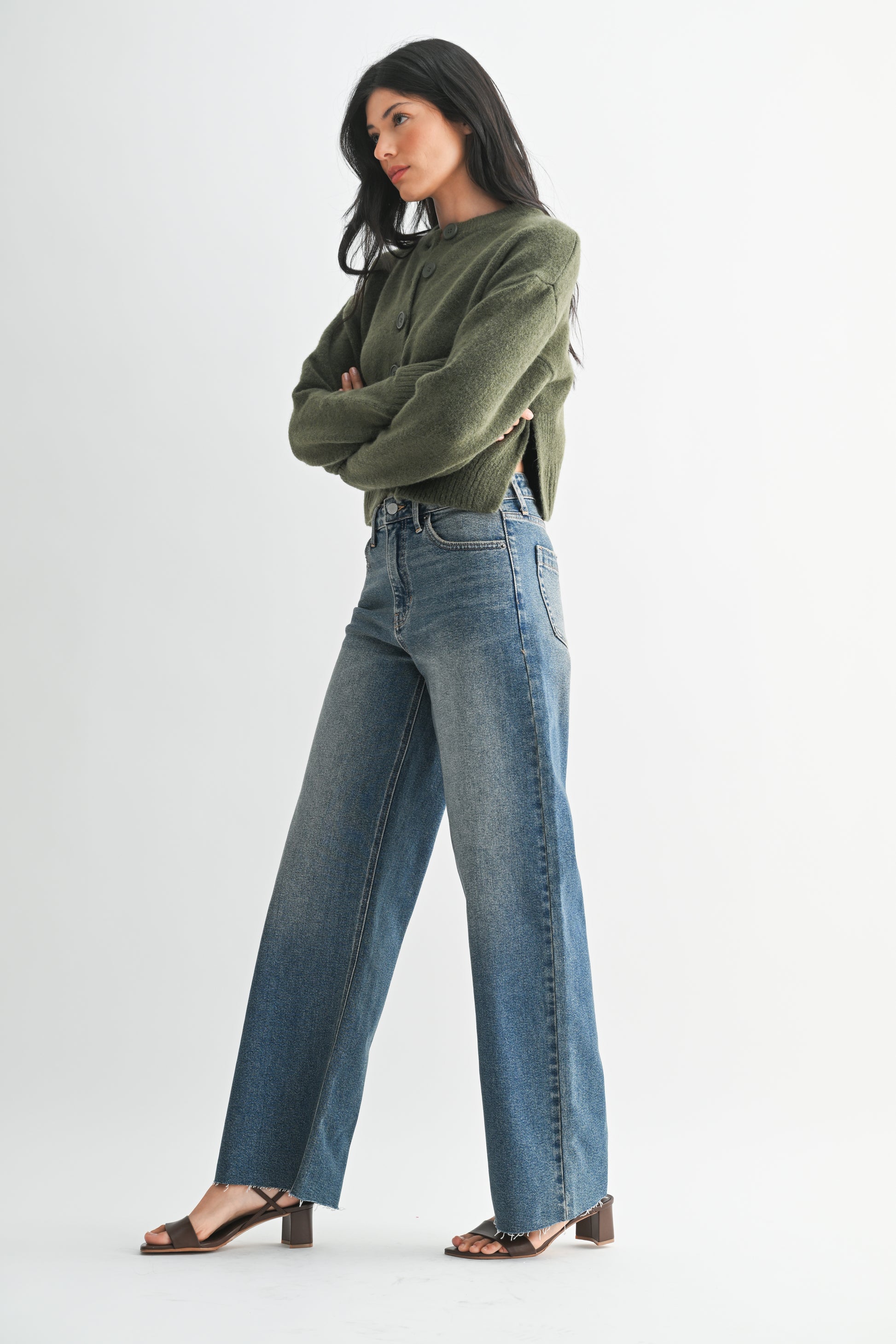 Woman wearing a green sweater and blue jeans on a white background