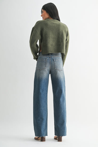 Person wearing a green sweater and blue jeans on a white background