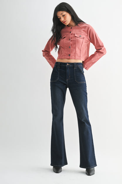 Woman wearing a pink denim jacket and dark blue jeans on a white background