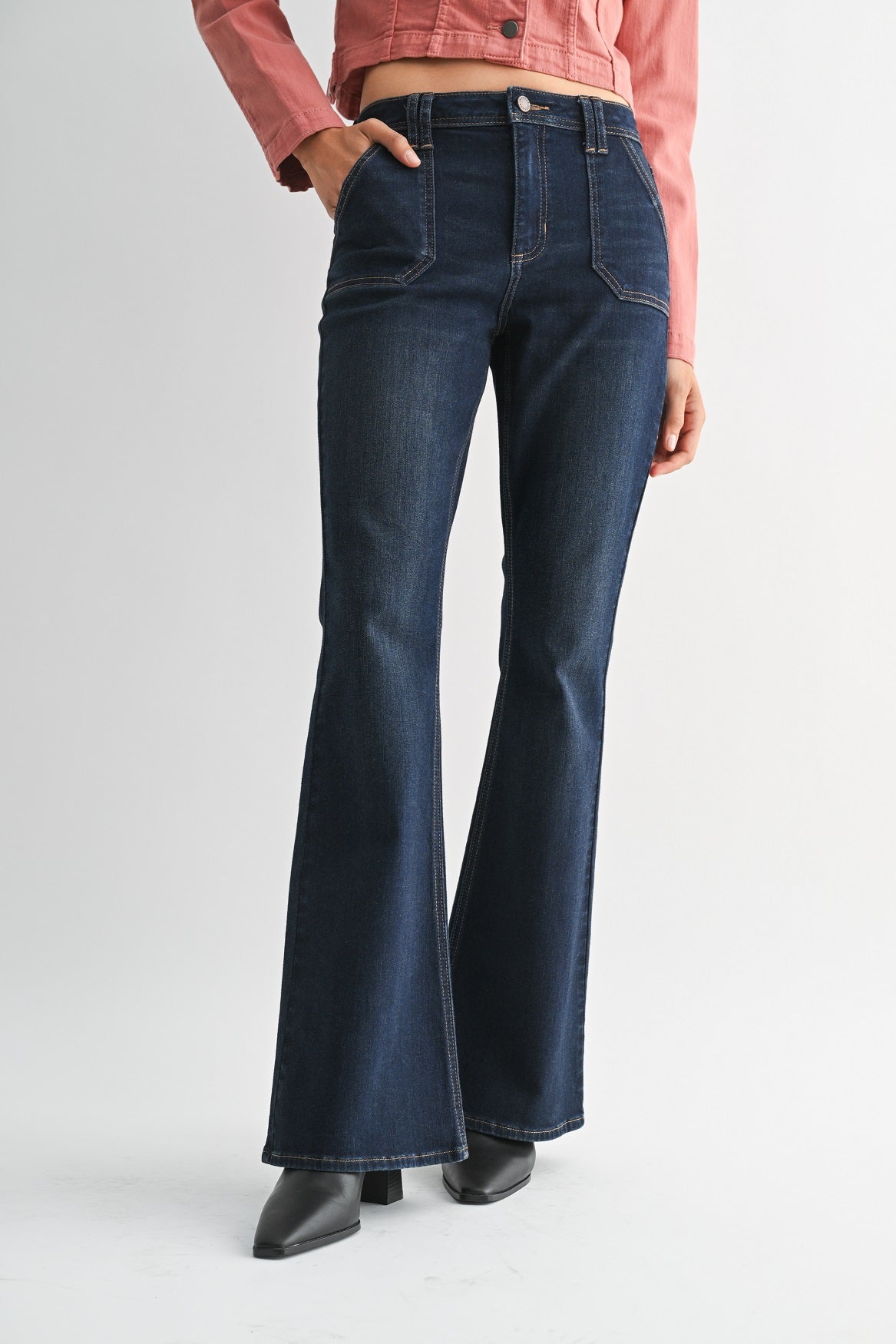 Woman wearing a pink denim jacket and dark blue jeans on a white background