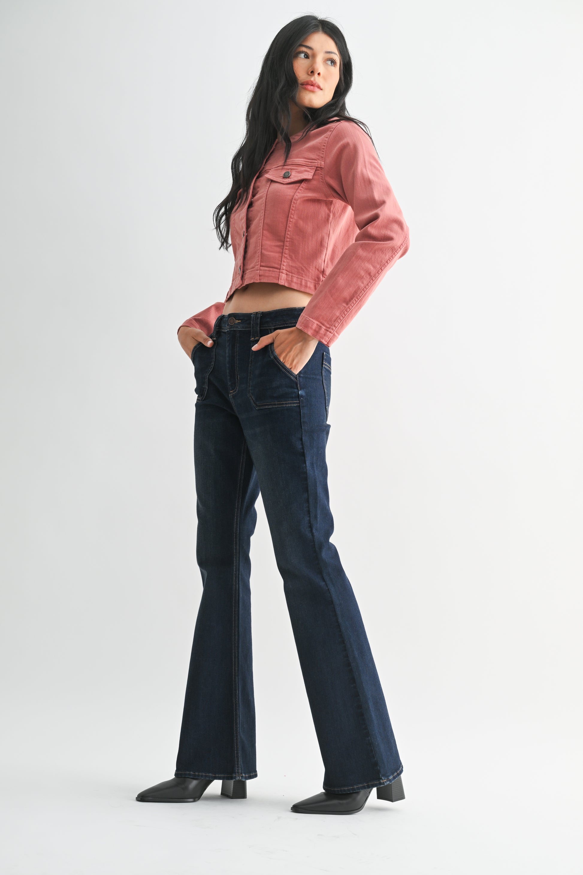 Woman wearing a pink jacket and blue jeans on a white background