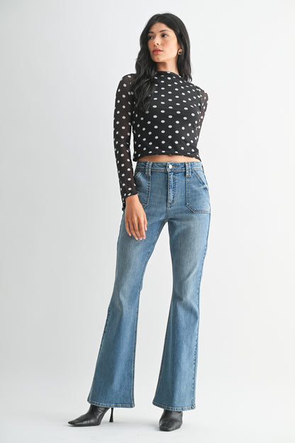 Woman wearing a black polka dot top and blue jeans on a white background