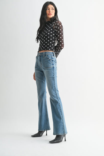 Woman wearing a polka dot top and blue jeans on a white background