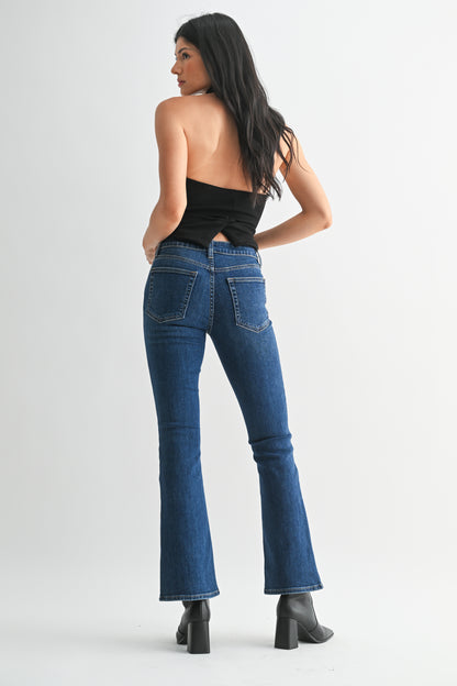 Woman wearing blue jeans and a black top on a white background