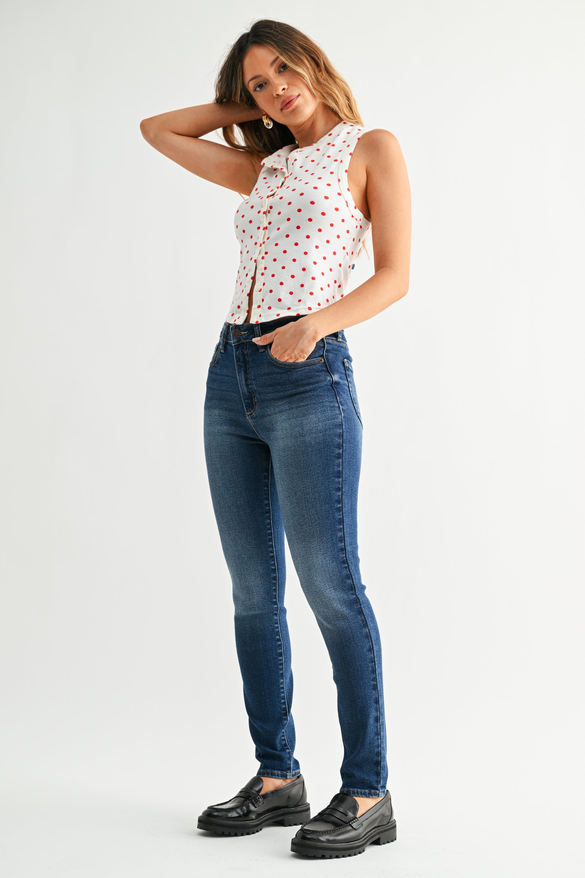 Woman wearing a white blouse with red patterns and blue jeans on a white background