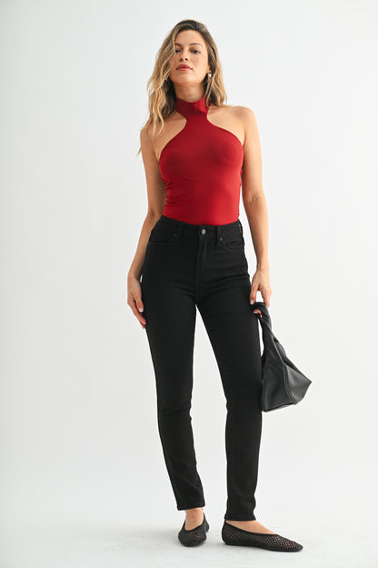 Woman wearing a red halter top and black pants on a white background