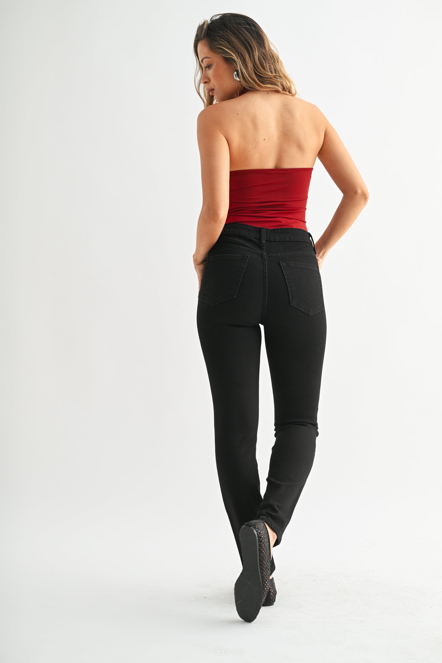 Woman wearing a strapless red top and black pants on a white background