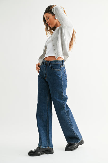 Woman wearing blue jeans and a gray top on a white background