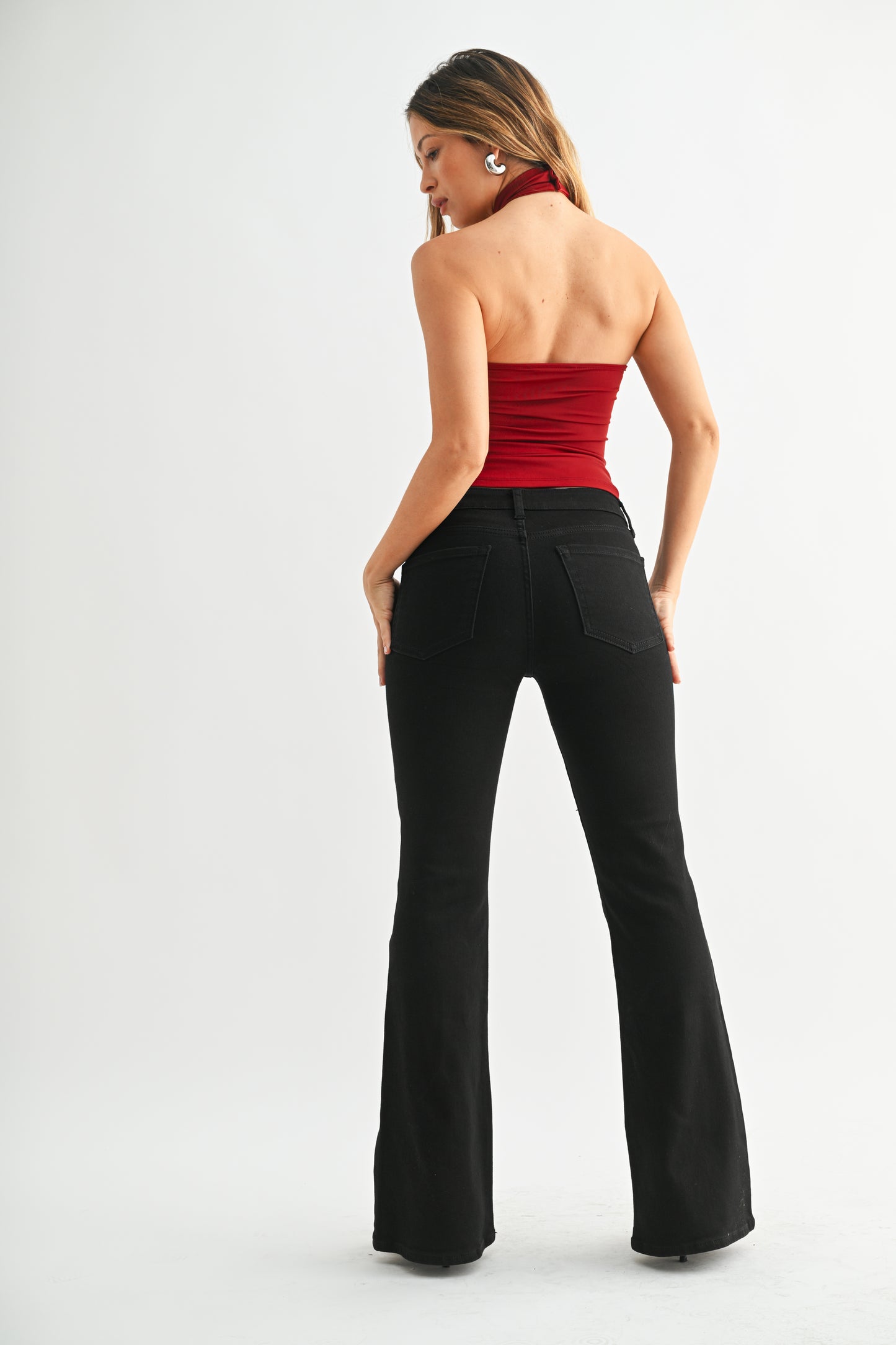 Woman wearing a red strapless top and black flared pants on a white background
