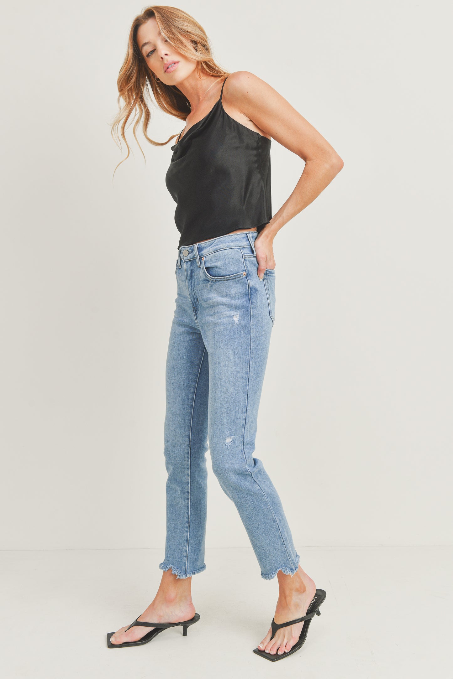 Woman wearing a black top and light blue jeans on a white background