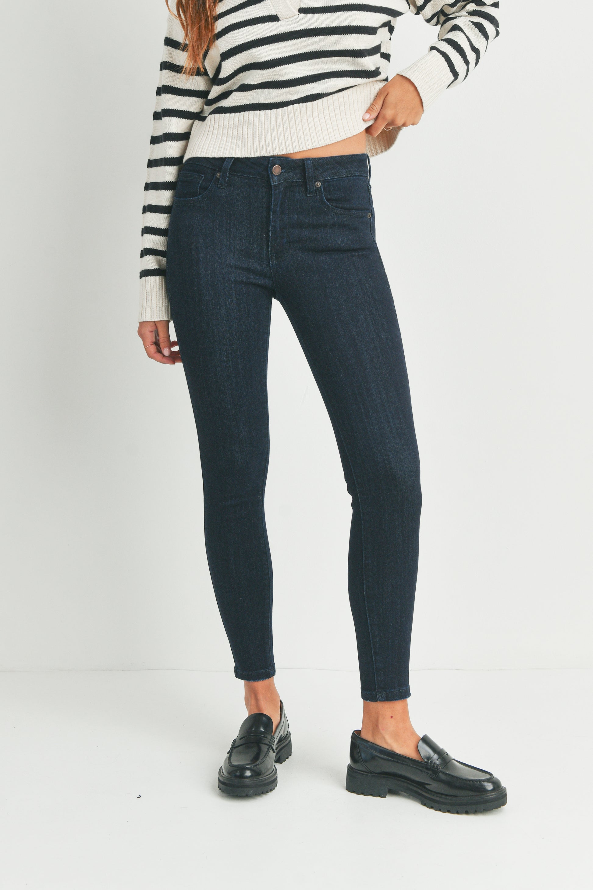 Person wearing dark blue jeans and a striped sweater on a white background