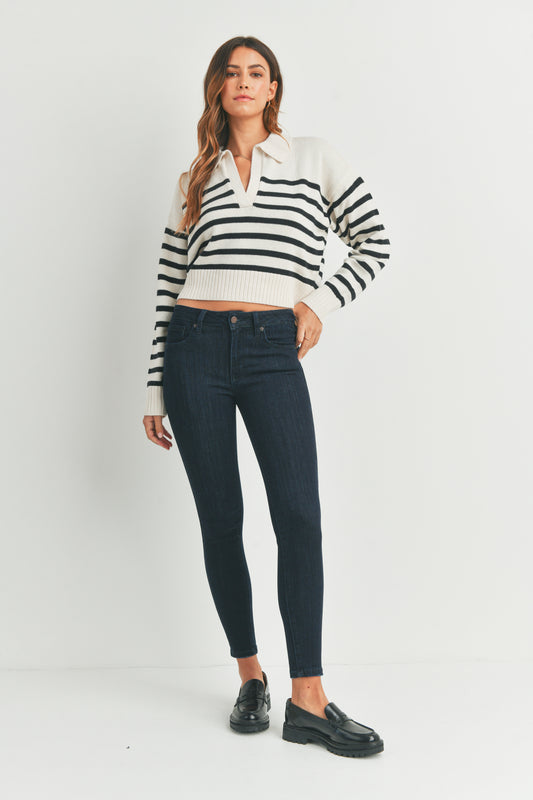 Woman wearing a black and white striped sweater and dark jeans on a white background