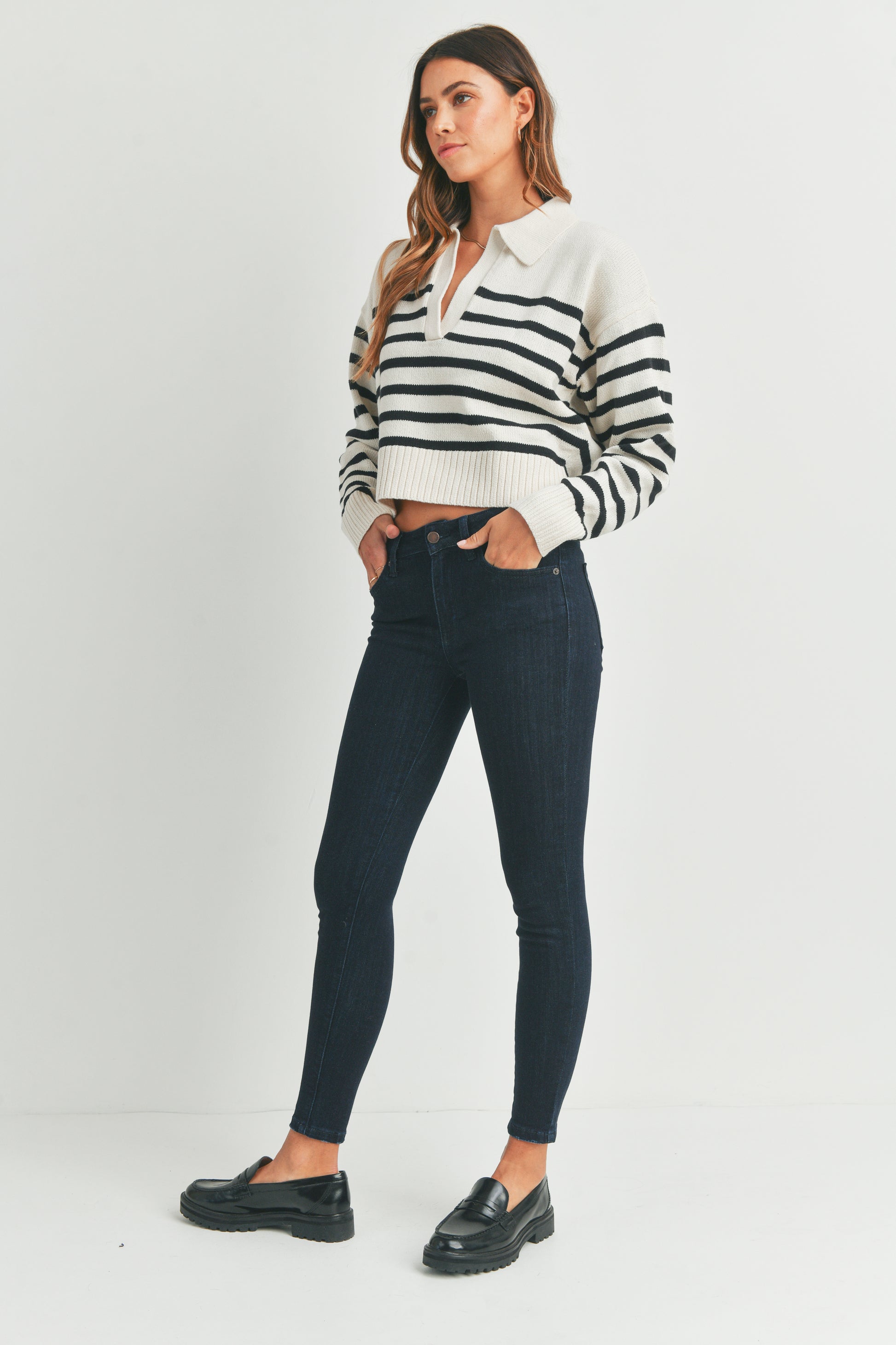 Woman wearing a black and white striped shirt with dark jeans on a white background