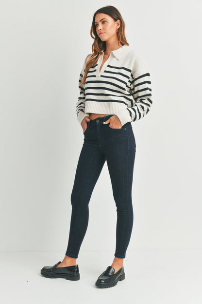Woman wearing a black and white striped shirt with dark jeans on a white background