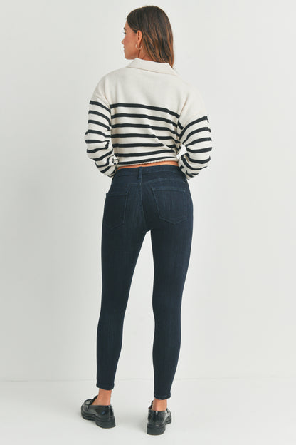 Woman wearing a striped sweater and dark jeans on a white background