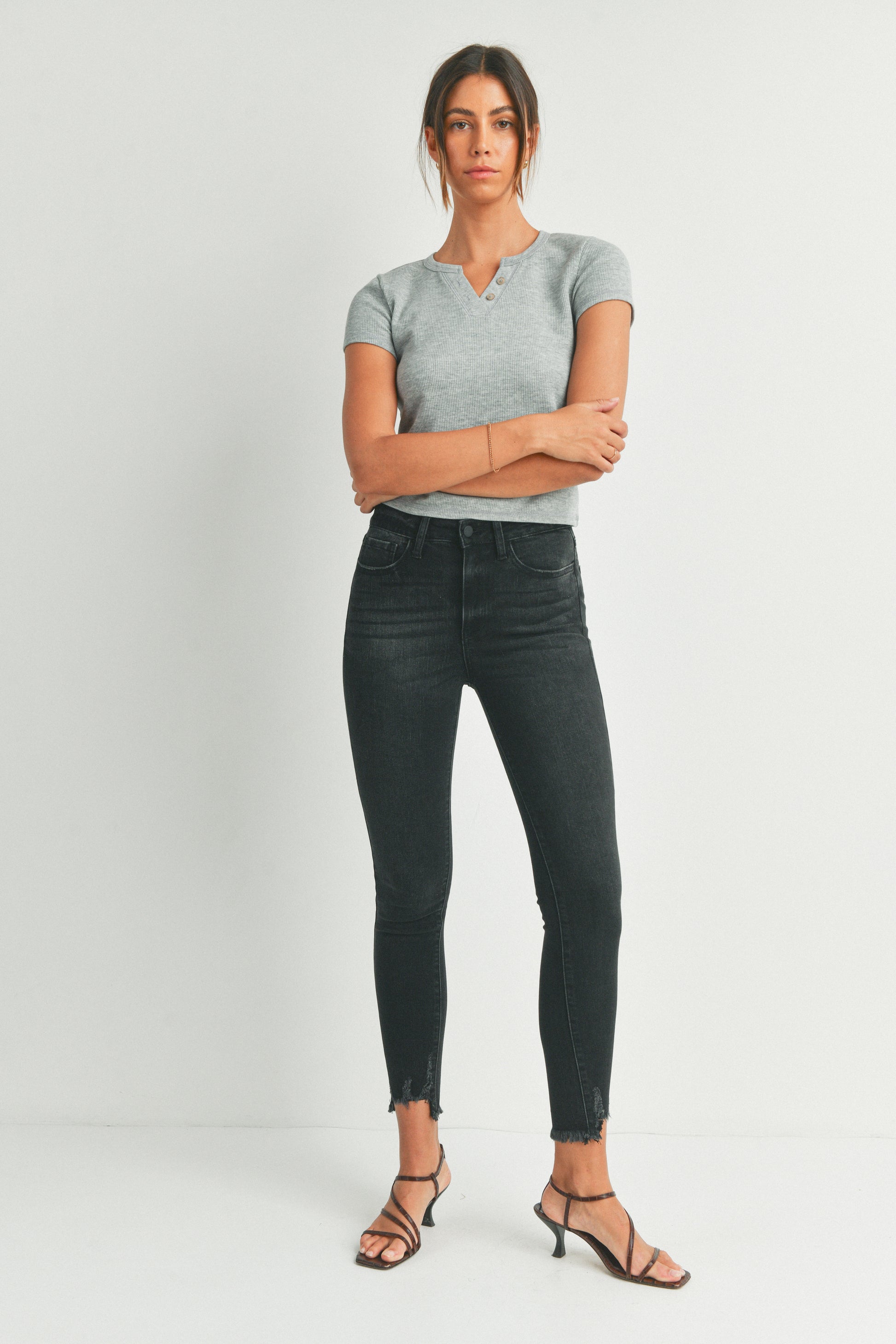 Woman wearing a gray t-shirt and black jeans on a white background