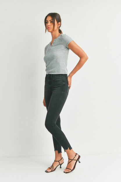 Woman wearing a gray top and black jeans on a white background