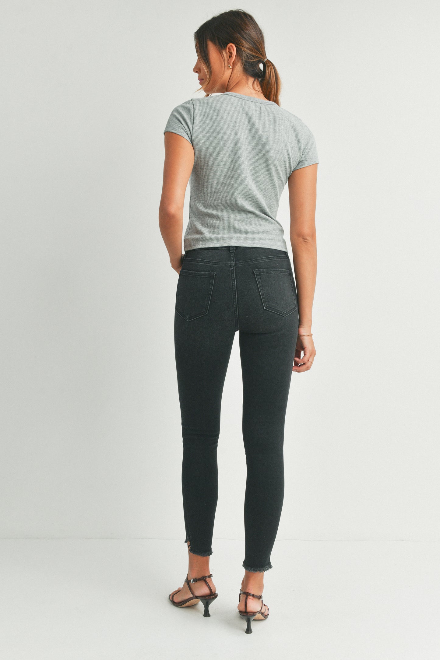 Woman wearing a gray t-shirt and black jeans on a white background