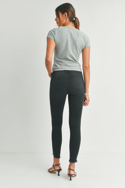 Woman wearing a gray t-shirt and black jeans on a white background