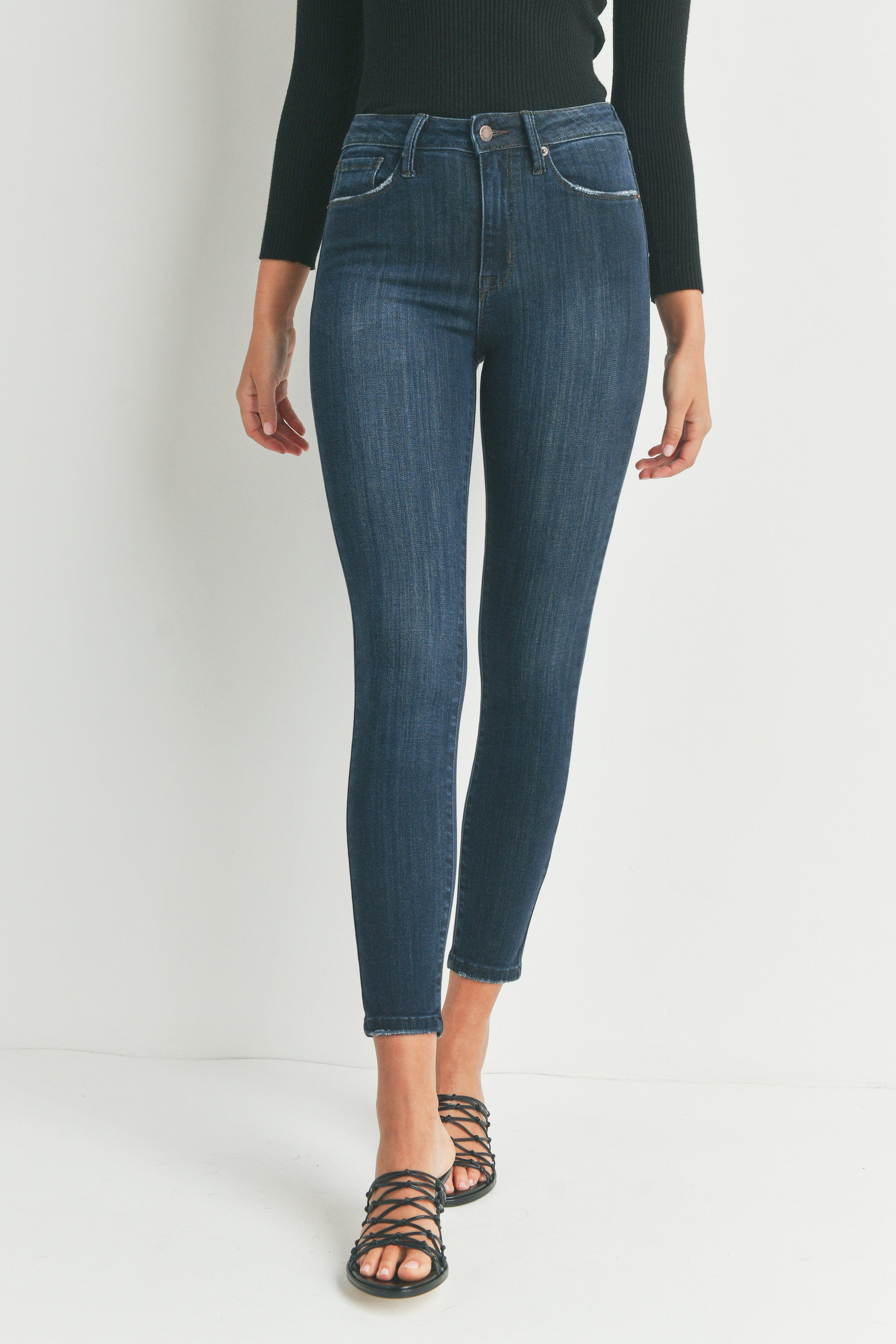 Person wearing blue jeans and a black top on a white background