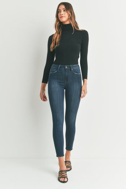 Woman wearing a black turtleneck and blue jeans on a white background