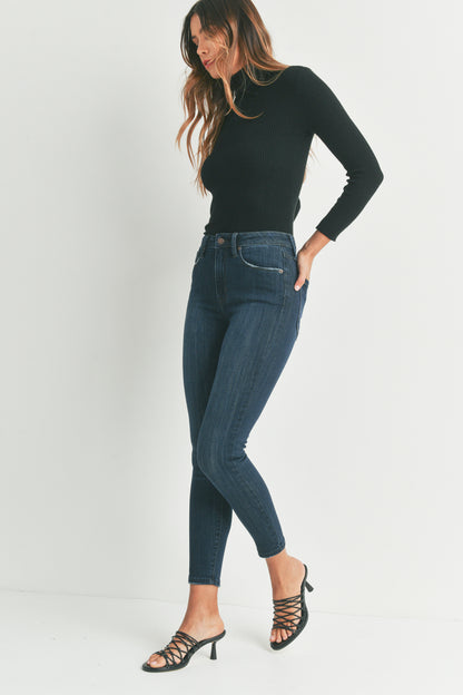 Woman wearing a black turtleneck and blue jeans on a white background