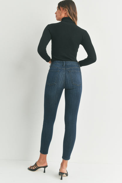 Woman wearing blue jeans and a black turtleneck on a white background