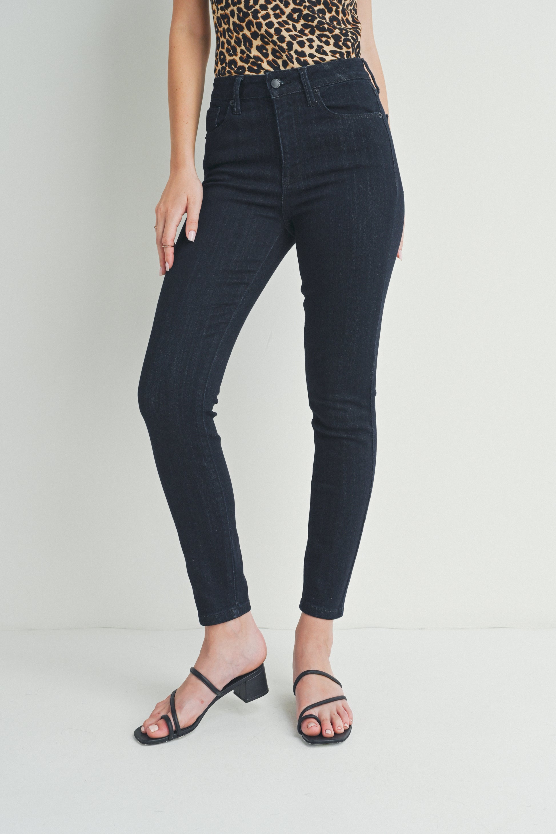 Person wearing black jeans and a leopard print top on a plain background