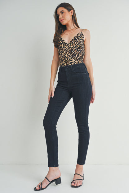 Woman wearing a leopard print top and dark jeans on a white background